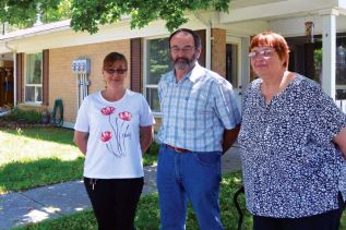 Christa Sheridan, Larry Pick, ad Linda Hume in front of the URCA senior's townhouse